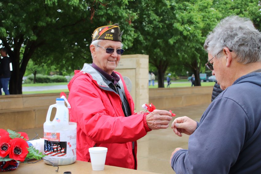 VFW member Jack Woodman passes out memorial poppies at Littleton's World War II memorial.